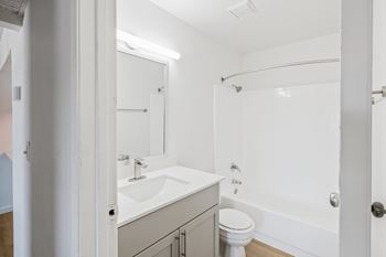 A white bathroom with a toilet, sink, and bathtub.
